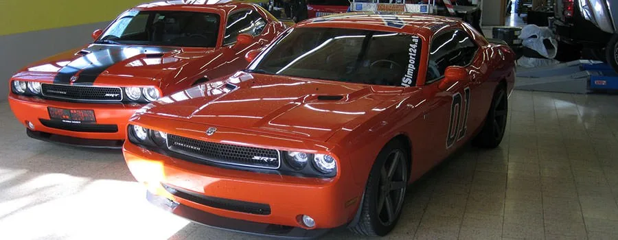 Zwei orangefarbene Fahrzeuge in der Werkstatt der Ländlegarage